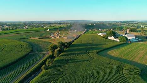 Dampfzug,-Der-An-Einem-Sommertag-Bei-Spätem-Sonnenuntergang-Durch-Amish-Ackerland-Und-Landschaft-Fährt,-Wie-Von-Einer-Drohne-Gesehen