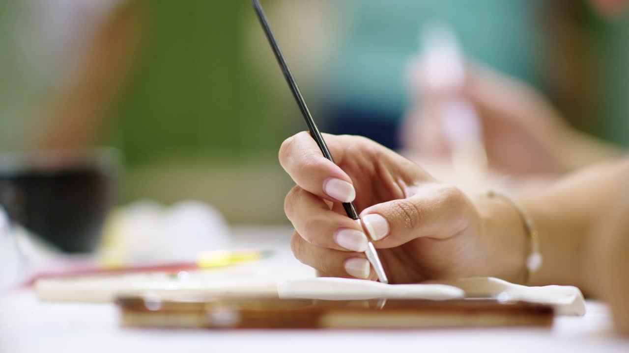Closeup of artist's hands painting ceramic on a workshop