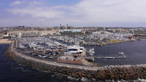 Low-panning-aerial-shot-of-the-King-Harbor-Yacht-Club-along-the-breakwater-in-Redondo-Beach,-California