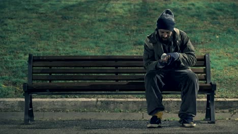 lonely beggar on bench cheking his money