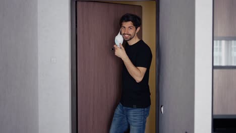 smiling man takes off his medical mask of coronavirus protection at home
