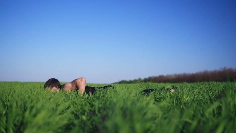 Young-man-doing-push-ups-with-arms-outstretched-for-a-workout.-Handsome-White-Caucasian.-Green-grass.-Sunny-day