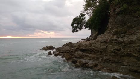 aerial-footage-flying-close-over-a-rocky-coastline-of-a-tropical-island-in-the-ocean