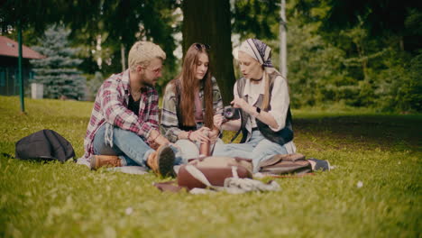 woman teaching friends about camera sitting at park