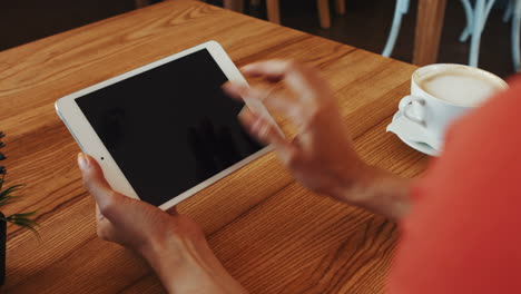 mujer usando una tableta digital mientras toma café