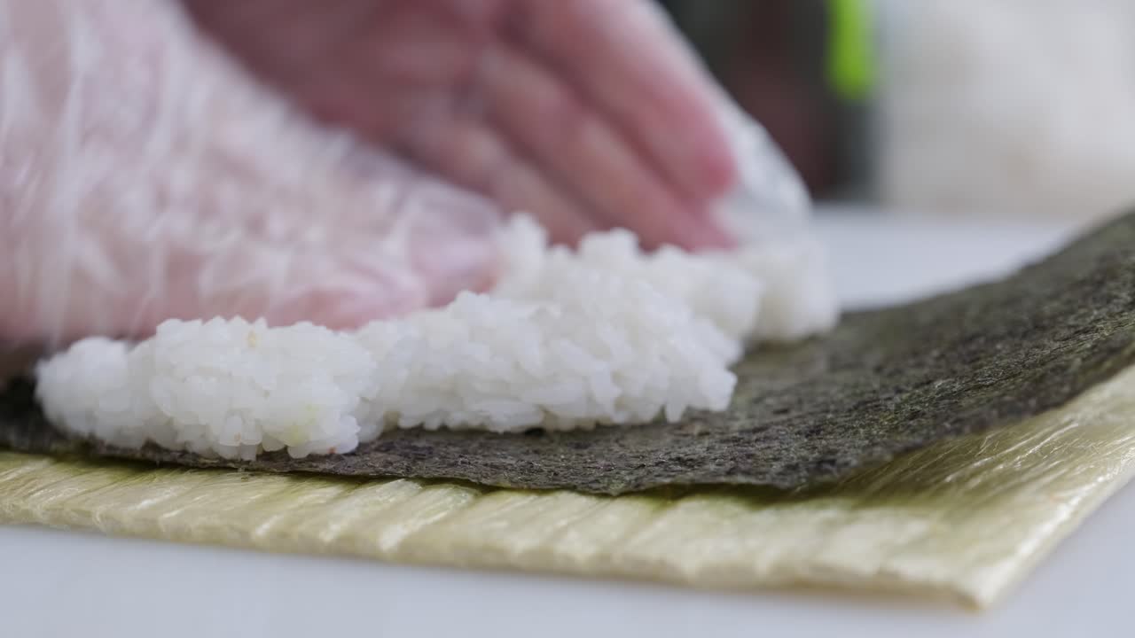 las manos aplastan el arroz en el nori.