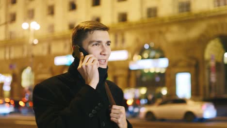 Young-man-talking-on-the-phone-against-the-backdrop-of-a-night-city-1