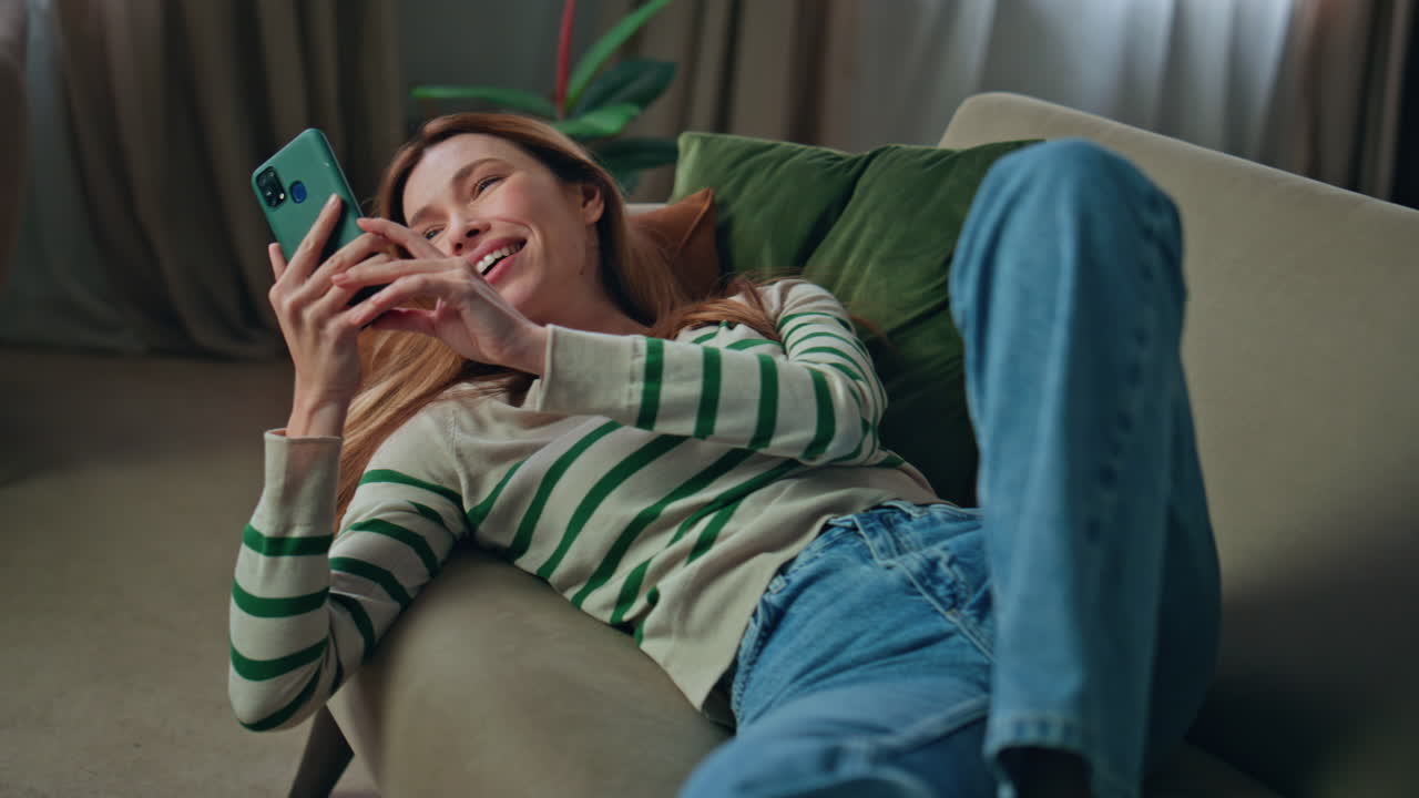 Relaxed girl greeting smartphone web camera lying couch closeup. Woman recording