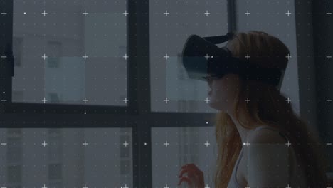 white particles moving over grid network against caucasian woman wearing vr headset at home