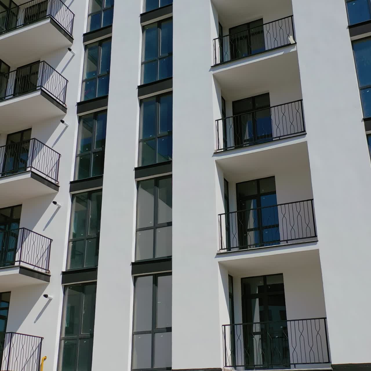 Facade of a newly built apartment building. Modern high-raised building with glass windows and balconies. Residential architecture.