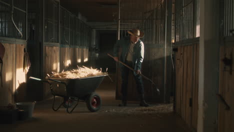 cowboy cleaning horse stable