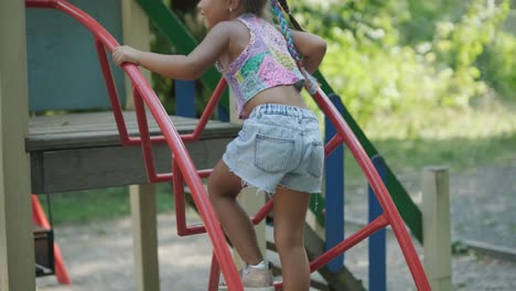 madre embarazada viendo a su hija jugar en el tobogán en el patio de recreo