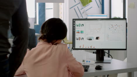 mujer de negocios hablando por teléfono con sus socios mientras el equipo trabaja en segundo plano