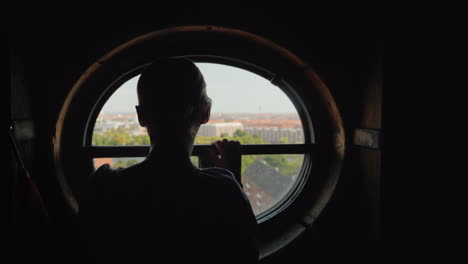 Silhouette-Einer-Frau,-Die-In-Einem-Runden-Fenster-Auf-Den-Dächern-Der-Stadt-Kopenhagen-In-Dänemark-Schaut