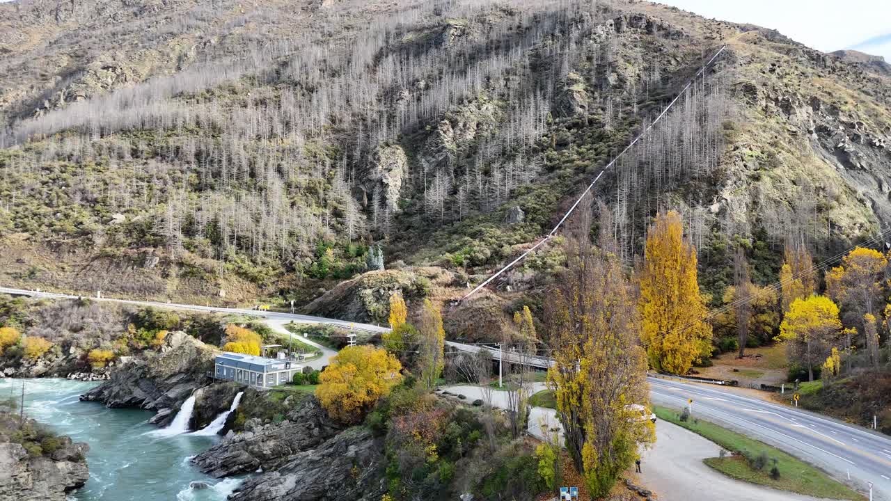 Drone footage captures the vibrant autumn landscape of Kawarau Gorge, showcasing the river, trees, and surrounding hills in Queenstown, New Zealand
