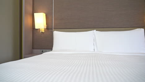 slow pan across a hotel bed made up with white sheets and pillows