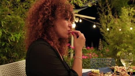 woman eating fish during dinner at the moody outdoor night restaurant