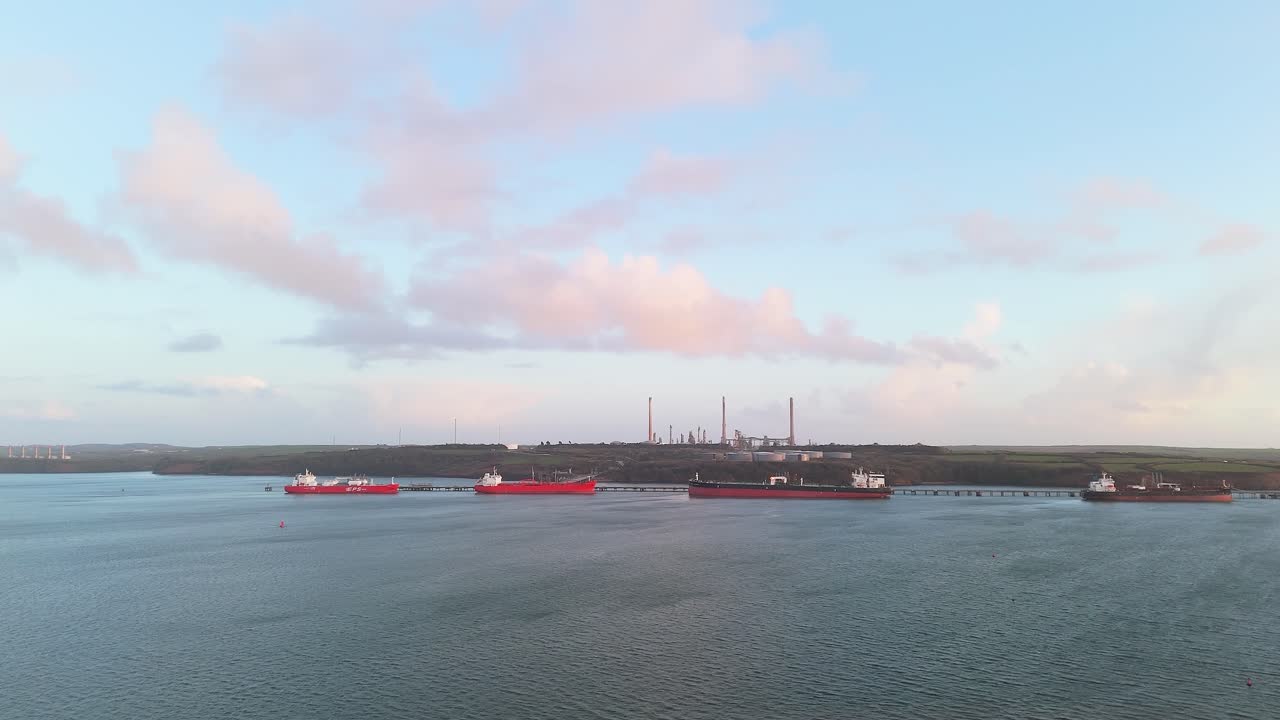 Red ships passing by valero pembroke refinery on a clear day, aerial view