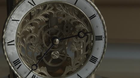 wider shot of ornate brass clock with hands stationary near three o'clock