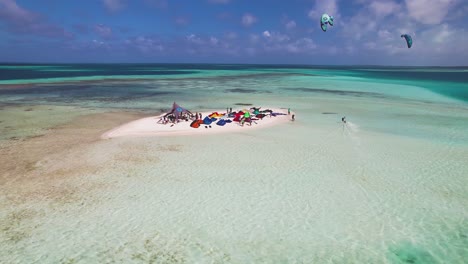 equipo de kitesurf y tienda en una isla de arena en medio de las aguas cristalinas del océano, los rocas