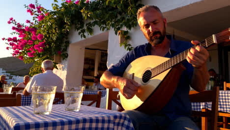 man playing a traditional string instrument at an outdoor mediterranean cafe