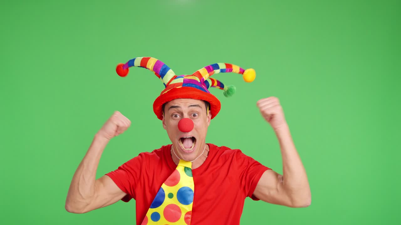 Euphoric clown pointing and showing on green chroma key background