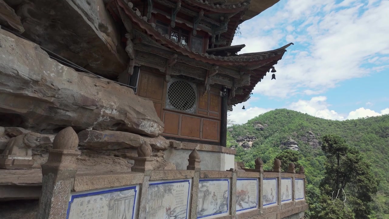 Balcone del tempio e ringhiera in pietra che si affacciano su montagne boscose nello Yunnan.