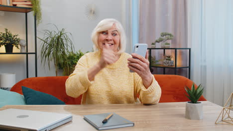 Mujer-Abuela-Mayor-En-Casa-Usa-El-Teléfono-Inteligente-Celebrando-El-éxito-Victoria-Ganando-Juego-En-Línea