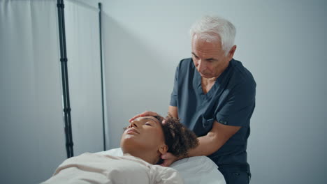 physiotherapist touch patient head in clinic ward. mature professional pressing