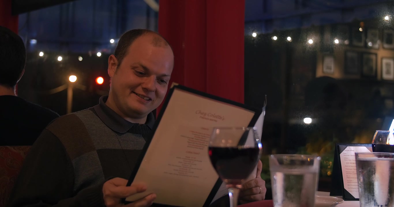Muž na romantické večeři mluví se svou partnerkou.