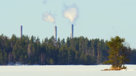 Neblina-De-Calor-Sobre-Un-Lago-Cubierto-De-Hielo-Con-Chimeneas-De-Fábrica-Fumando-En-El-Fondo