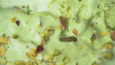 close-up top-down shot of a creamy pistachio ice cream scoop with scattered raw nuts for texture
