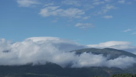 vuelo de avión no tripulado en el valle de tiétar-ávila en una mañana donde vemos con un giro de la cámara que las nubes se han pegado a las montañas también hay nubes bajas y un cielo azul, hermoso paisaje