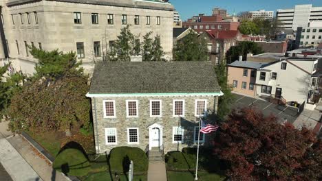 Histórica-Casa-De-Piedra-Y-Museo-Con-La-Bandera-Estadounidense-Cerca-De-Los-Edificios-Gubernamentales-De-La-Casa-Estatal-En-El-Centro-De-Trenton,-Nueva-Jersey