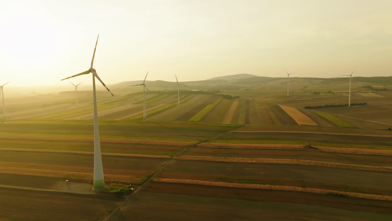 vista aérea de las turbinas eólicas que generan energía activamente sobre las tierras de cultivo al amanecer