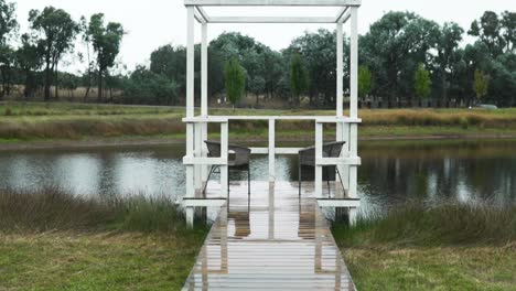 muelle de madera con sillas vacías en un lago tranquilo - toma amplia