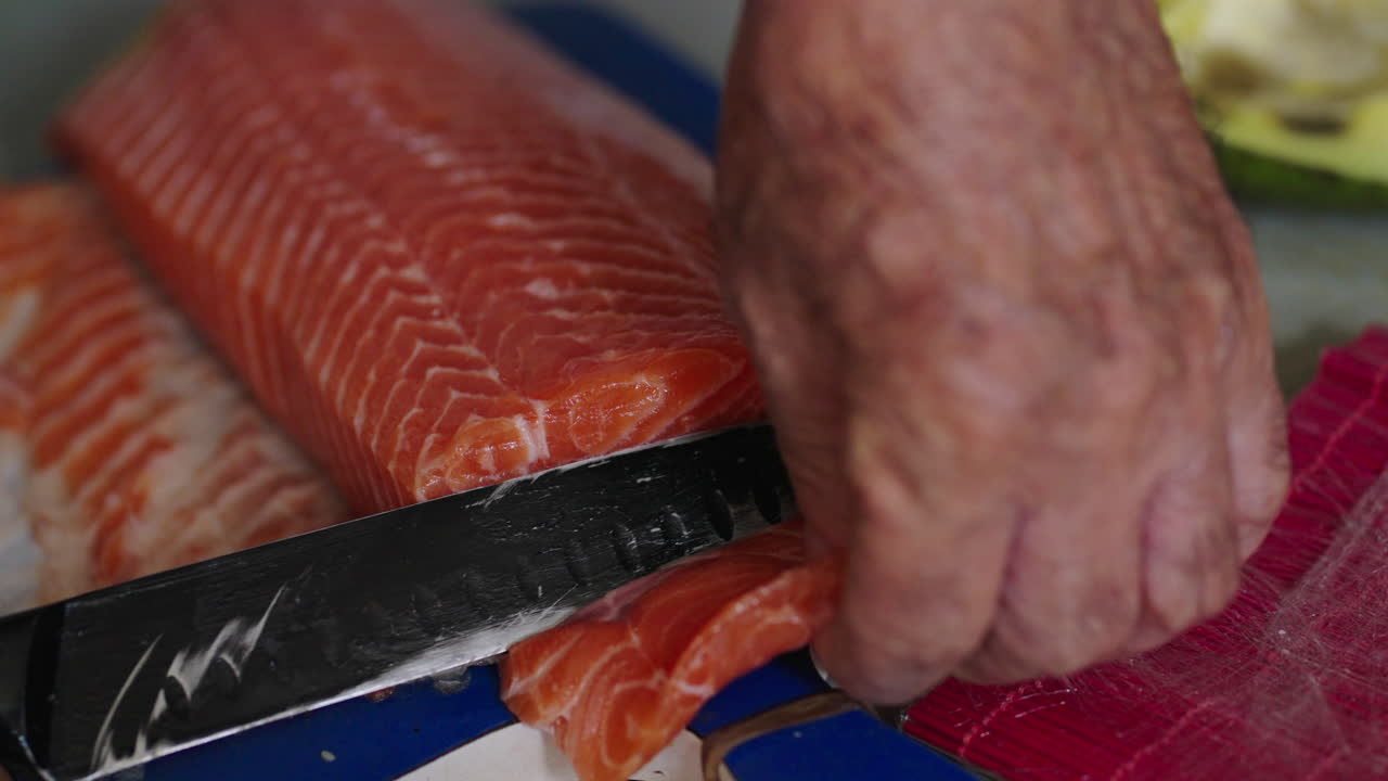 Fresh salmon being sliced for sushi in professional food prep, close-up