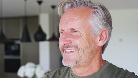 Smiling-Senior-Man-Standing-And-Looking-Out-Of-Kitchen-Door