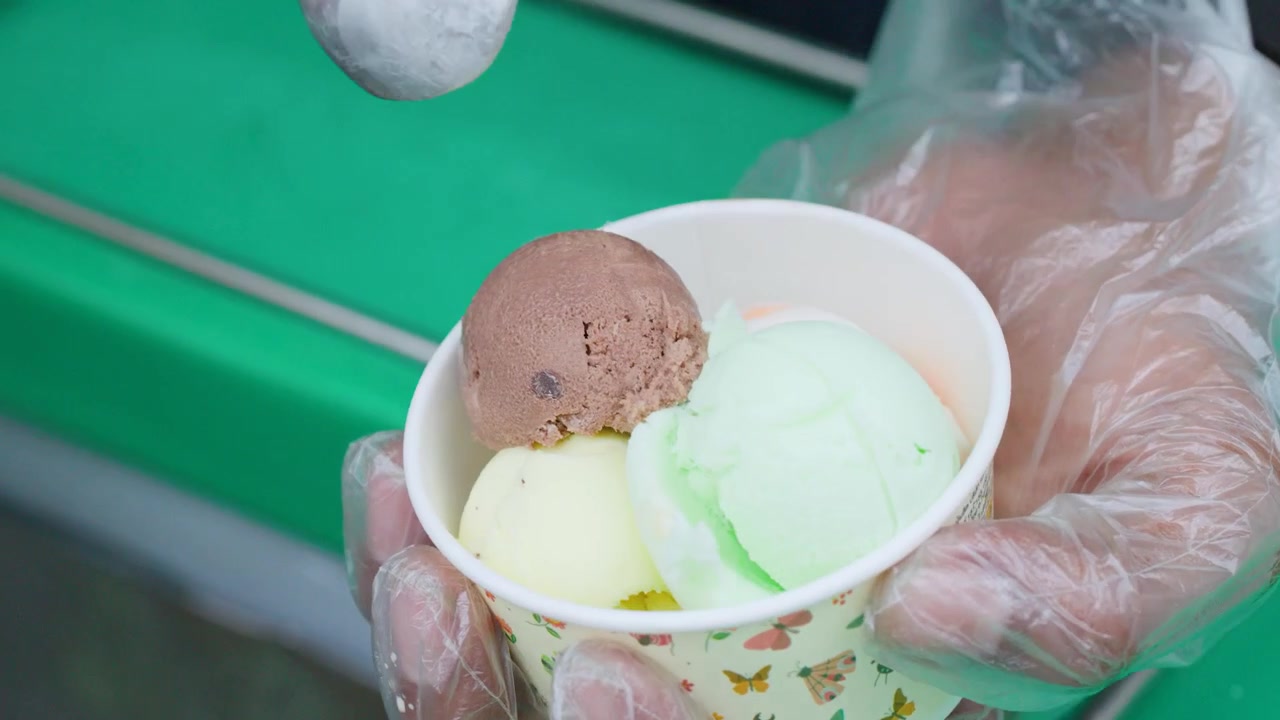 Cameriere che serve diversi gusti di gelato in una coppetta di carta