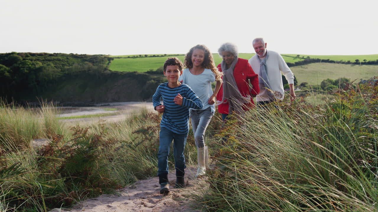 abuelos mayores activos caminando a lo largo del camino costero con nietos en el otoño juntos