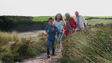 Abuelos-Mayores-Activos-Caminando-Juntos-Por-El-Sendero-Costero-Con-Sus-Nietos-En-Otoño