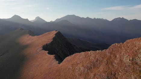 Un-Excursionista-Parado-En-La-Cima-De-Una-Montaña-En-Los-Pirineos-Franceses-Durante-Una-Puesta-De-Sol-Dorada-Que-Muestra-Hermosos-Rayos-De-Luz,-Cresta-Montañosa-Y-Naturaleza-Remota