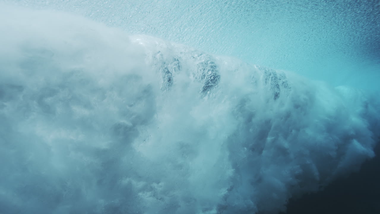 Underwater barrel wave forming a smooth arc with textured blue water and motion