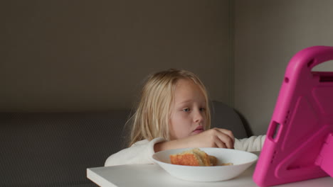 girl eating breakfast while using tablet