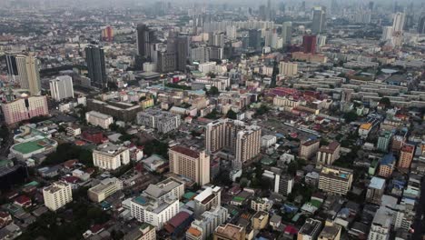 Aerial-tilts-up-to-highrise-skyscrapers-in-downtown-Bangkok,-Thailand