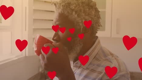 animation of hearts over african american man drinking coffee