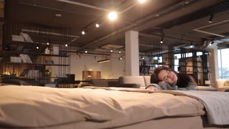 young woman sleeping sweetly on comfortable mattress in furniture store. high quality 4k footage