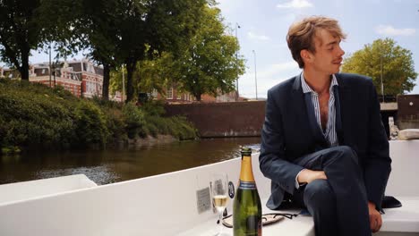 young guy with mustache relaxing on white boat in amsterdam canals