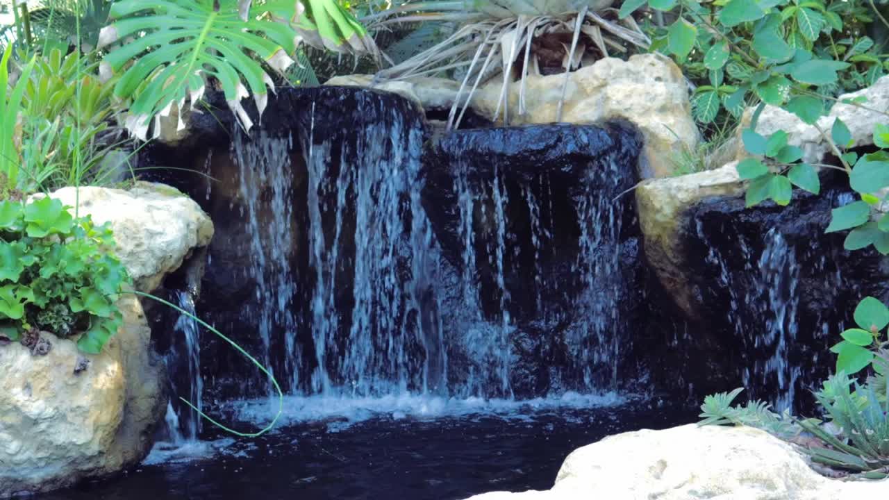 Una cascata da giardino circondata da pietre e piante.