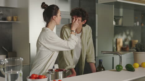 couple playfully cooking and sharing food in kitchen